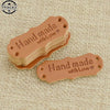A stack of brown PU leather sewing labels with the text Hand made with Love on them.