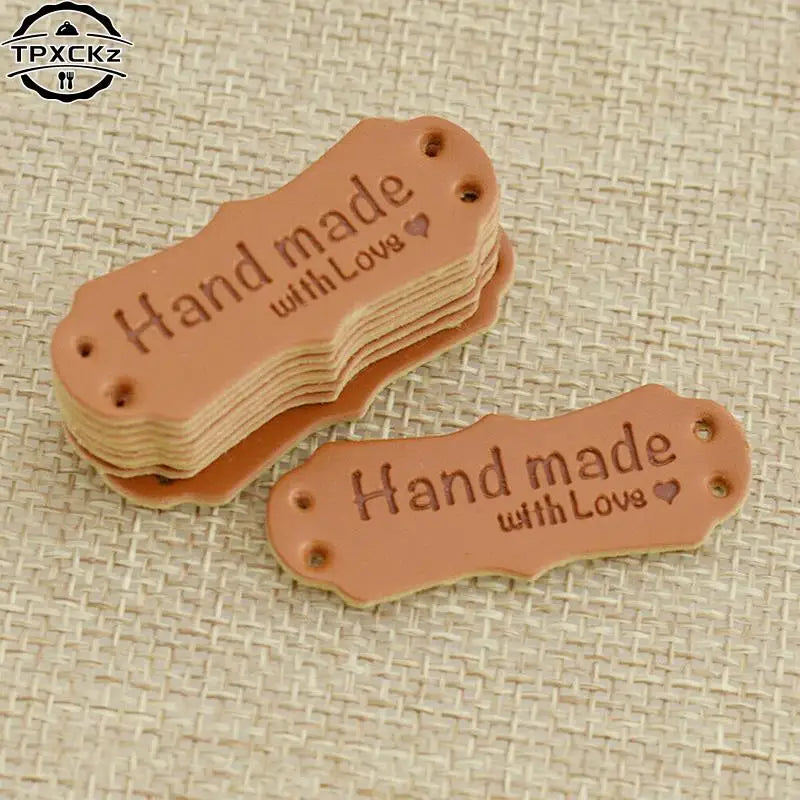A stack of brown PU leather sewing labels with the text Hand made with Love on them.