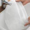 A hand is holding a white dust cover over a sink while water flows from a metal faucet.