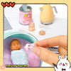 A pink baby doll is shown next to a yellow teapot and a small pink accessory kit.