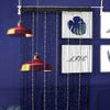 A dark blue beaded string curtain with a white leaf design hangs in front of a window.