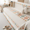 A beige bohemian jacquard sofa cover featuring geometric patterns and decorative pillows on a light-colored sofa.