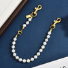 Gold and pearl chain keychain featuring a letter C detail against a dark blue background.