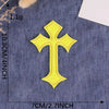 A yellow embroidered cross patch on a dark blue fabric background.