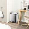 A modern stainless steel trash can with a soft-close lid and step pedal sitting on a wooden desk.