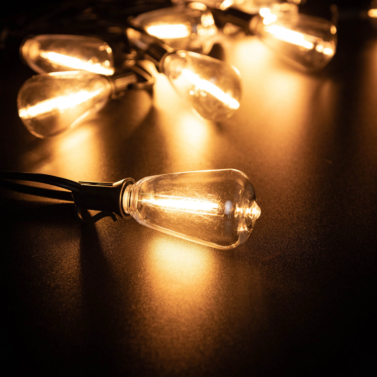 A close-up shot of a glowing vintage-style light bulb, part of a solar string light setup.
