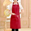 A woman wearing a red cotton apron over a white shirt standing in a brightly lit room.