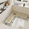 An L-shaped crystal velvet kitchen mat with a black and white patterned border is displayed on a white countertop.
