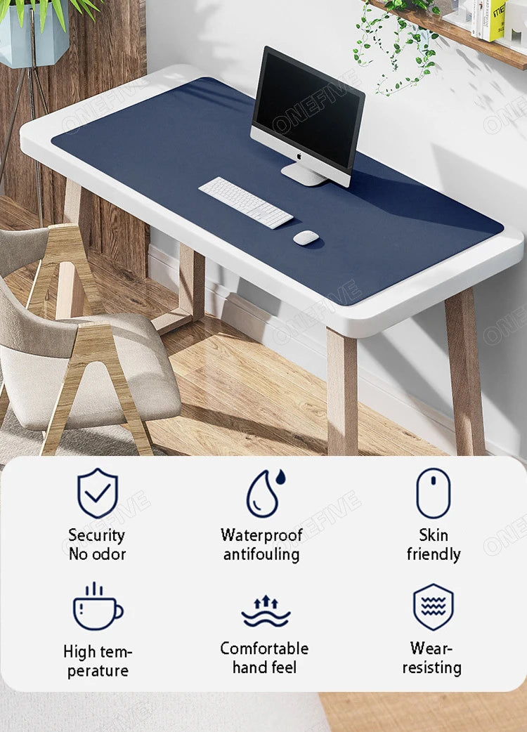 A dark blue premium PU leather desk mat with a black monitor and keyboard on a wooden desk.