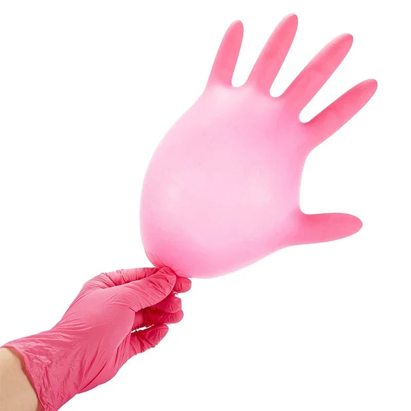 A hand wearing a pink disposable nitrile glove is shown holding another pink glove.