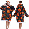 Eine Frau modelliert einen gemütlichen, patchworkartigen, oversized Fleece-Hoodie mit Kürbis-Designs in Orange vor dunklem Hi