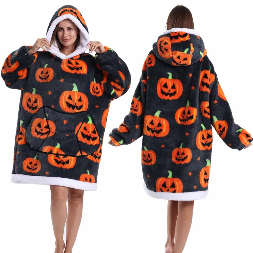Eine Frau modelliert einen gemütlichen, patchworkartigen, oversized Fleece-Hoodie mit Kürbis-Designs in Orange vor dunklem Hi