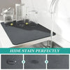 A black absorbent kitchen drying mat is shown next to a kitchen sink with a faucet, demonstrating its ability to hide stains.