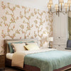 A bedroom featuring a bed with a headboard and white walls decorated with a floral self-adhesive wallpaper roll.