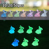 A set of ten resin miniature bunny figurines in various pastel colors arranged on a dark surface.