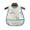 A white baby feeding bib with a blue trim and a catch pocket hanging on a wooden hanger.