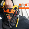 A hand holds a black and orange heavy duty magnetic drill holster attached to a tool bag.