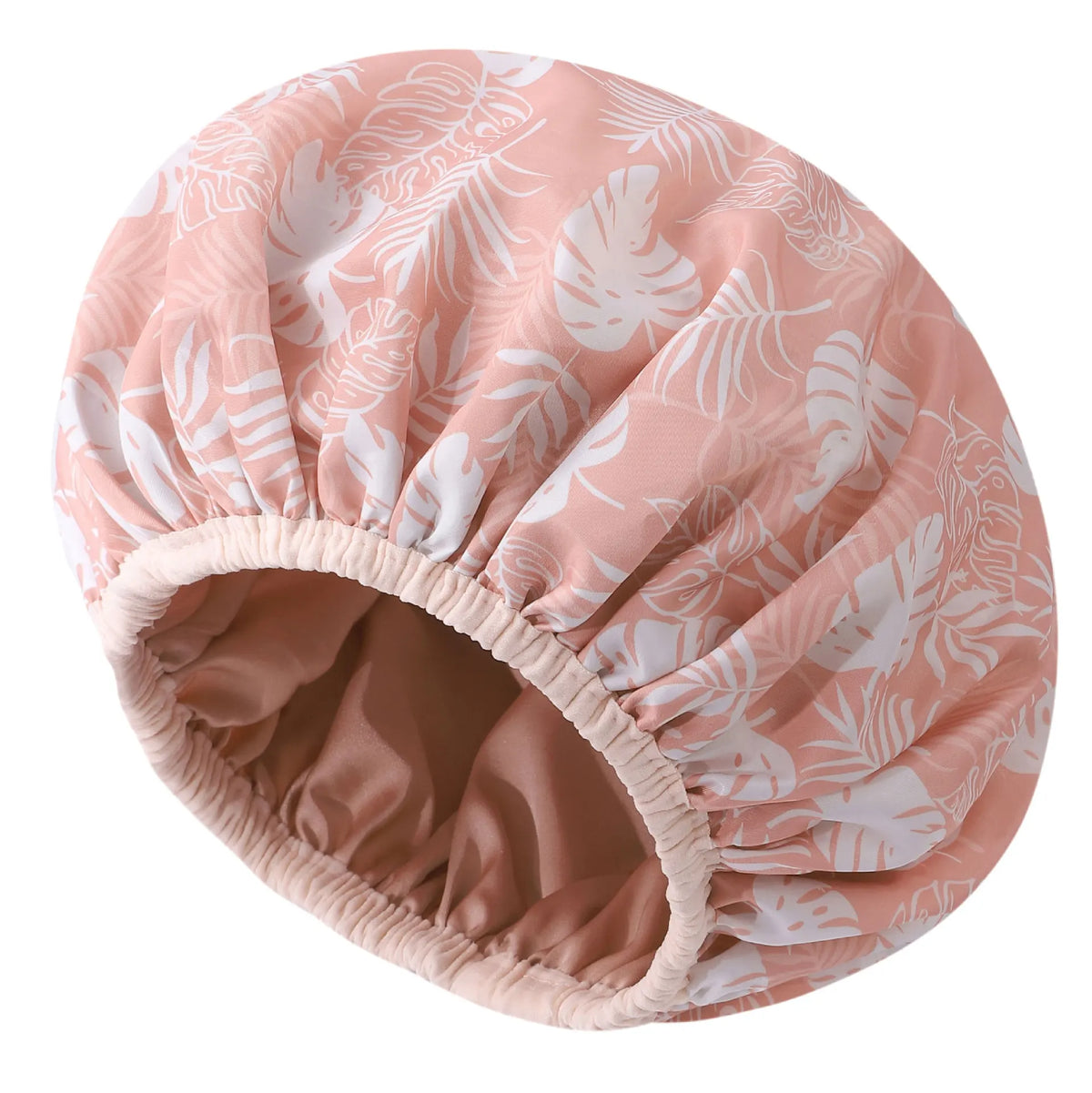 A large pink and white tropical leaf patterned satin-lined waterproof shower cap for hair protection