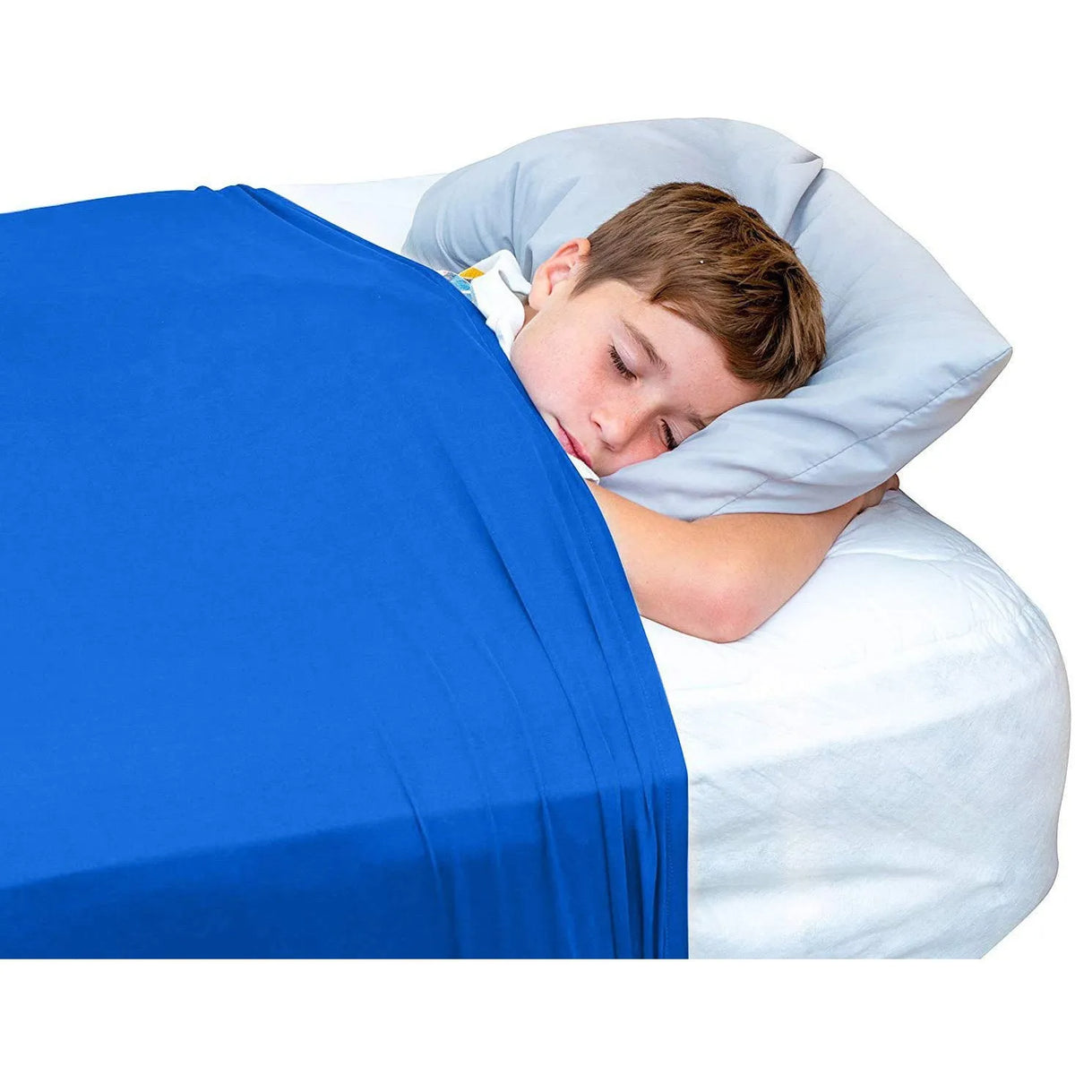 A young boy is resting his head on a light gray pillow while lying on a bright blue bed sheet.