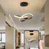 A hand holds a smartphone displaying a modern LED pendant light fixture in a bright interior setting.
