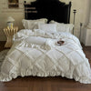 A white ruffled duvet cover set with matching pillowcases displayed on a bed against a dark wooden headboard.