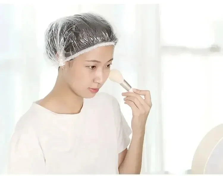 A person is applying a white product to their hair while wearing a disposable shower cap.