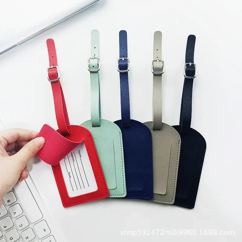 A hand holds a classic PU leather luggage tag in various colors including red, green, blue, and black.