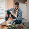 A man is organizing a roll-up multi-pocket tool organizer bag with various tools on a wooden table.