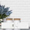 White subway tiles with glass jars and blue flowers displayed against a white brick wall background