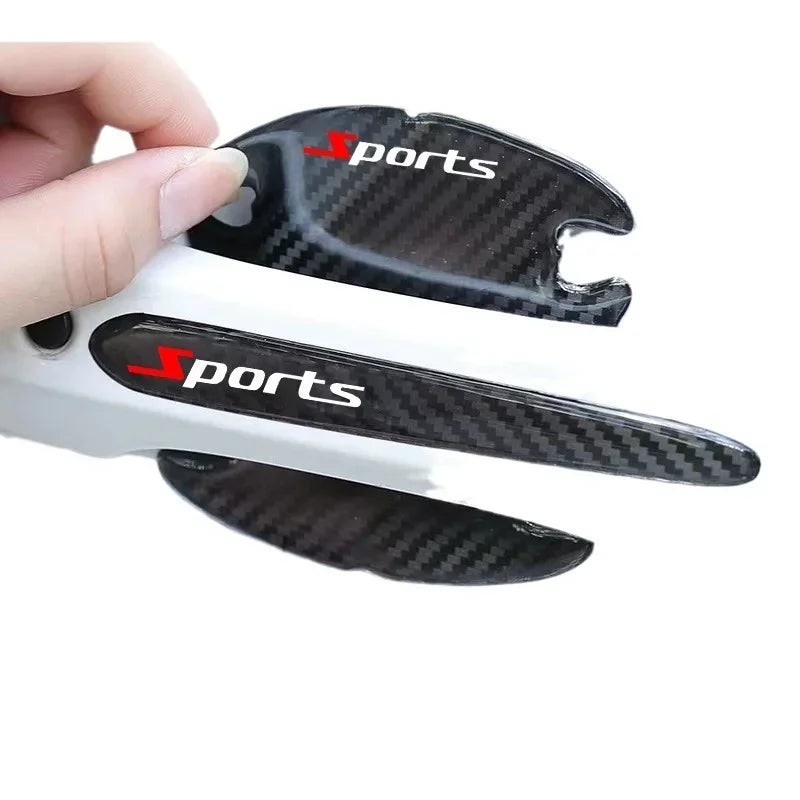 A hand holds a set of black carbon fiber door handle protectors with the sports logo on a white background.