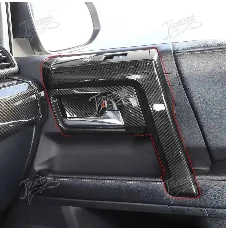 Close-up of a black carbon fiber trim kit installed on the interior panel of a vehicle.