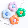 A collection of five colorful, flower-shaped silicone phone grips in pastel and bright tones.