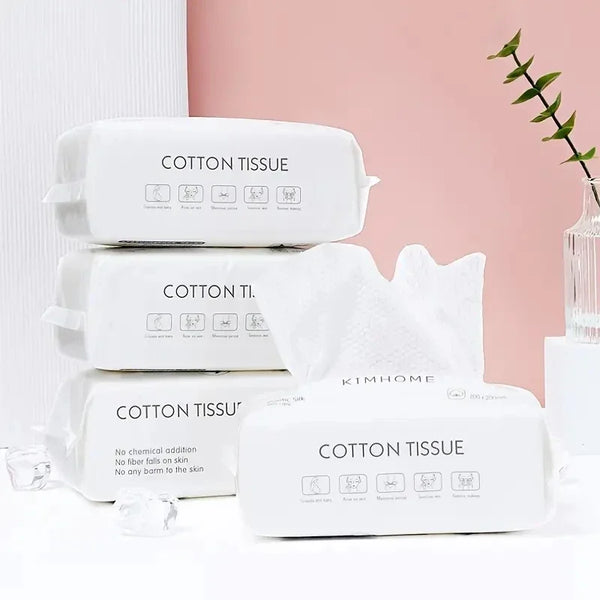 A stack of white disposable cotton tissue packs for facial cleansing and skincare.