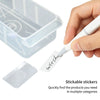 A hand is holding a white stickable sticker and placing it into a clear plastic organizer box.
