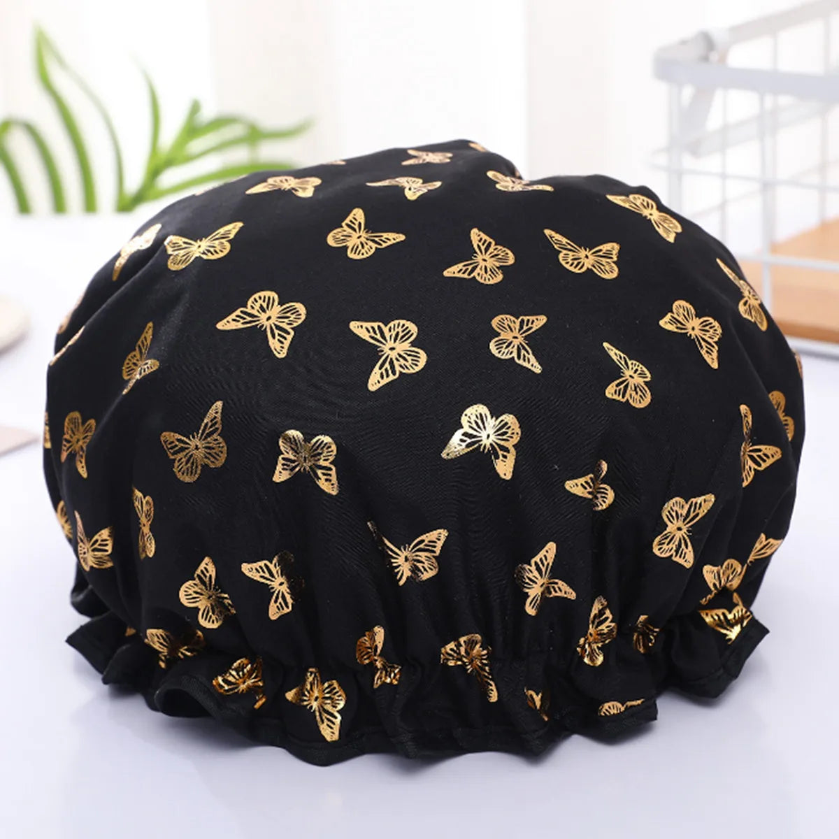 Black reusable elastic shower cap adorned with gold butterfly patterns
