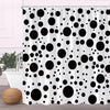 Black and white polka dot fabric shower curtain with hooks hanging in a bathroom