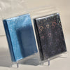 A pair of holographic heart-shaped card sleeves in blue and dark gray are displayed inside clear plastic packaging.