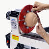A hand is operating an aluminum oxide sandpaper roll assortment with a dispenser on a grinding machine.
