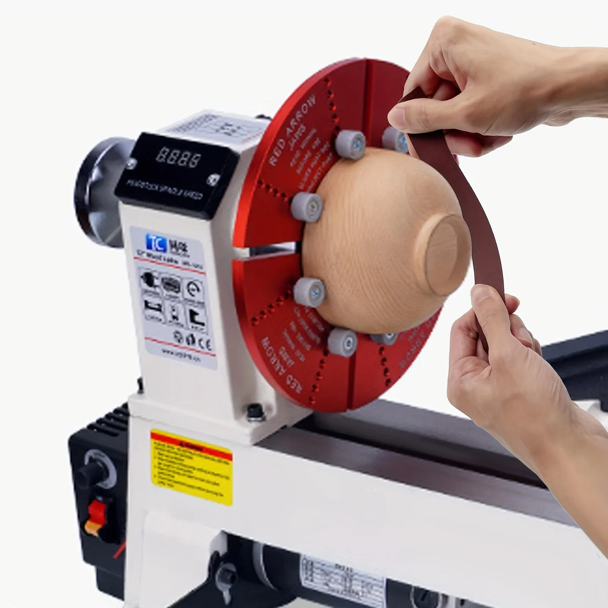 A hand is operating an aluminum oxide sandpaper roll assortment with a dispenser on a grinding machine.