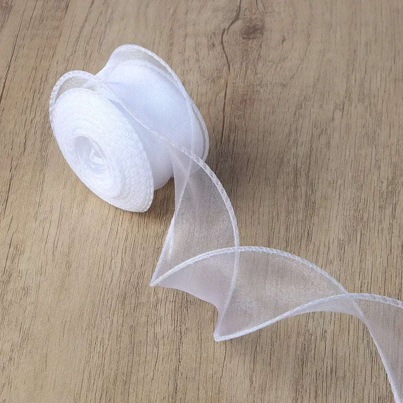 Roll of sheer white organza ribbon unwinding on a wooden surface