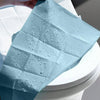 A light blue disposable toilet seat cover with water droplets is shown on a white toilet.