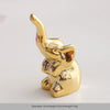Gold-colored ceramic elephant and rabbit jewelry holder with a curved horn design.