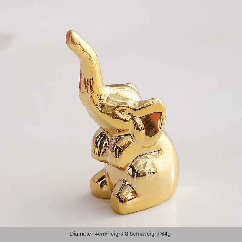 Gold-colored ceramic elephant and rabbit jewelry holder with a curved horn design.