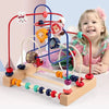 A wooden bead maze toy with colorful beads and rings is set up on a light wooden base for toddlers.