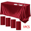 A deep red satin tablecloth draped on a table with silverware and wine glasses set for formal dining.