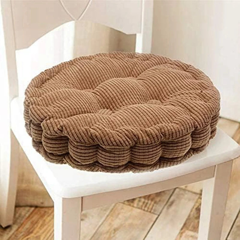 A thick brown corduroy floor cushion is placed on a white wooden chair.