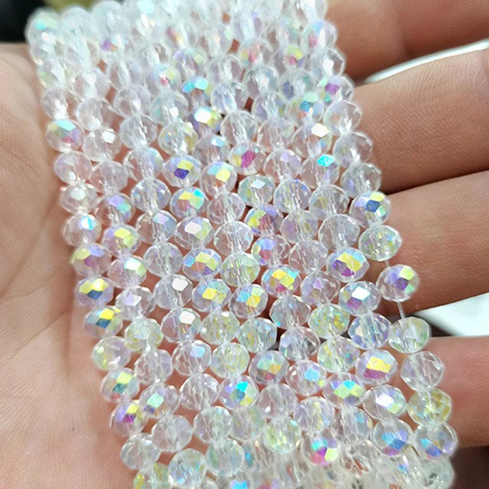A close-up of clear faceted crystal glass spacer beads arranged on a hand.