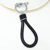 A black braided leather key fob cover with a silver split ring attached to a gold-colored cord.
