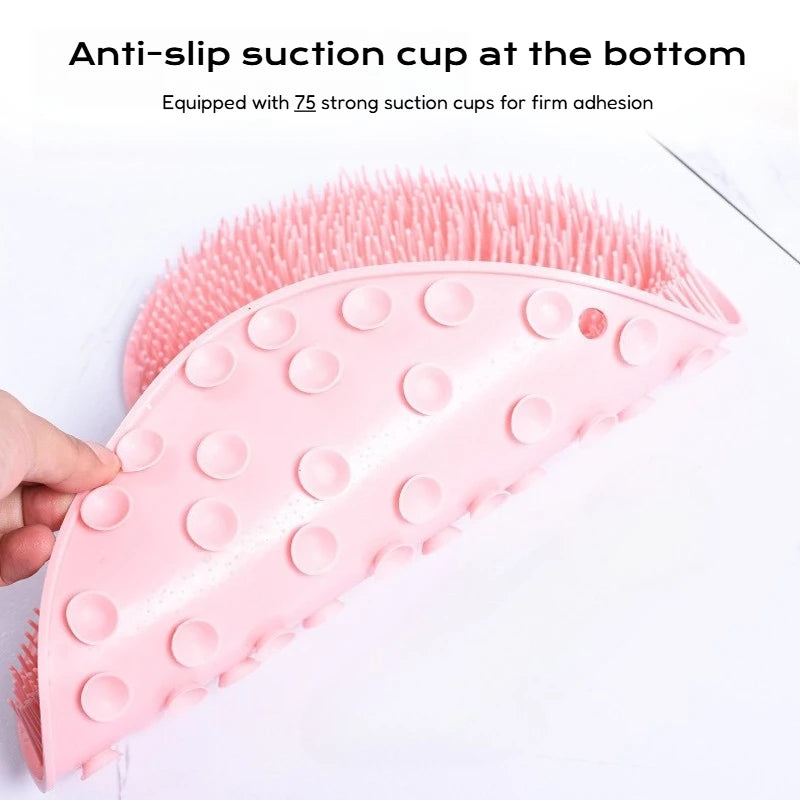 A pink suction cup foot massage mat with exfoliating bristles is shown being held by a hand.