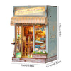 A miniature DIY book nook kit featuring a detailed shelf scene with a wooden facade and glass display.